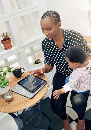 Bonding while browsing. Shot of a mother sitting with her baby girl and using a digital tablet.の写真素材