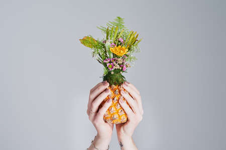 For the love of all things beautiful and natural. Shot of an unrecognizable woman holding a pineapple stuffed with flowers.の写真素材