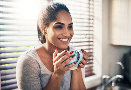 Coffee is where good vibes come from. Cropped shot of a beautiful young woman,enjoying a cup of...