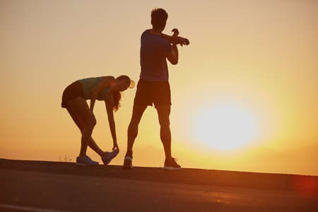 Feeling the burn and loving it. Shot of a silhouetted couple out for a run at sunrise.の写真素材