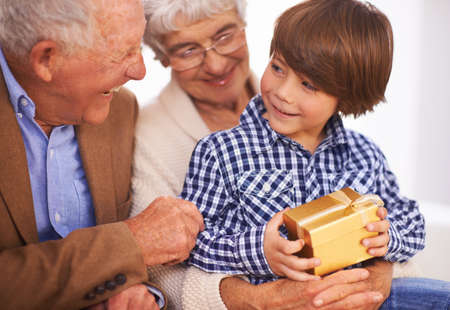 Grandparents always spoil their grandkids. A young boy getting a gift from his grandparents.の写真素材