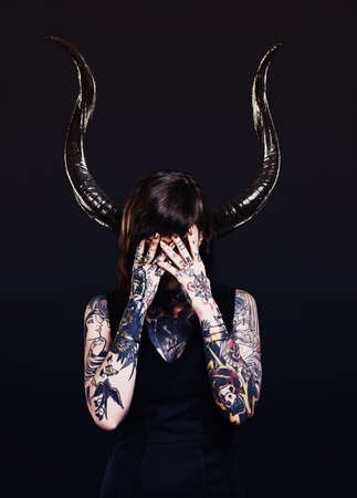 The dark side. Studio shot of a tattooed young woman.の写真素材