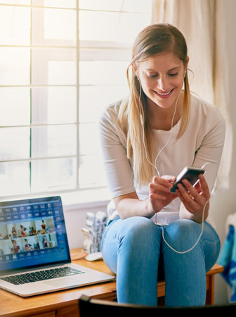 Choosing some tunes for her next study session. Shot of a young woman using her smartphone while...
