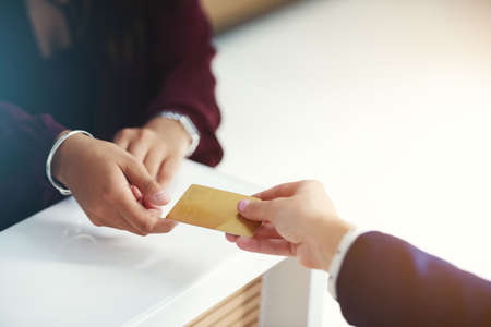 Put it on my card. Cropped shot of an unrecognisable person handing over a credit card for payment.の写真素材