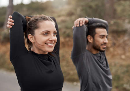 Youre always one run away from a different life. Cropped shot of two young athletes stretching before exercising outdoors together.の写真素材