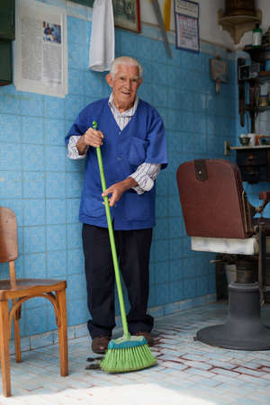 He always make sure his shop is clean for customers. Shot of a senior man working in his barber shop.の写真素材