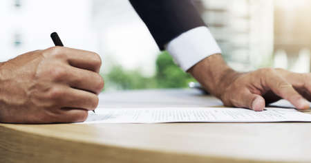 The deal is signed for. Closeup shot of an unidentifiable businessman going through paperwork in an...