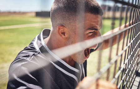 If youre not passionate about it youre not a fan. Shot of a young man watching a game of baseball from behind the fence.の写真素材