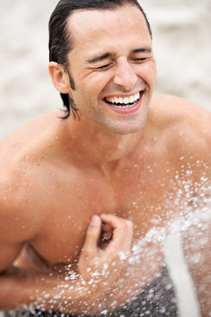 Power shower. Shot of a handsome young man enjoying a refreshing shower.の写真素材