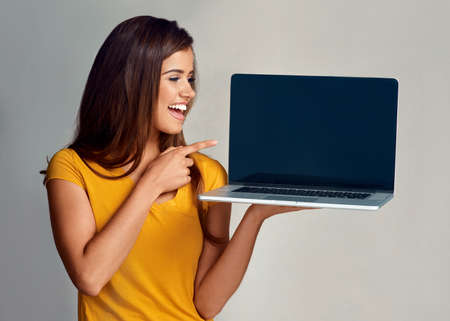 Itll be worth your while to check this out. Studio shot of an attractive young woman pointing to a...