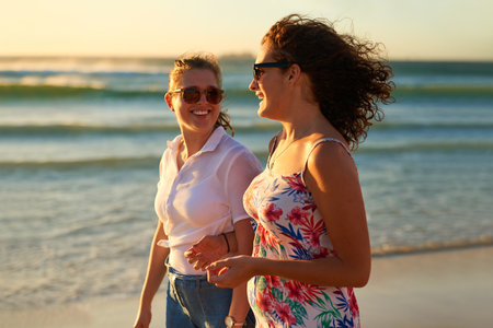 Who doesnt love a beach day with bestie. Cropped shot of two attractive young girlfriends having a chat while strolling on the beach.の写真素材