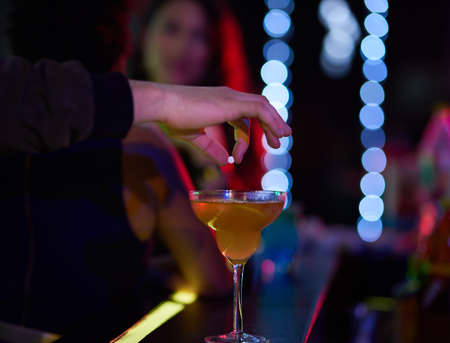 Never leave your drink unattended. Closeup shot of a man dropping a pill into a womans cocktail in a...