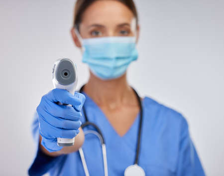 I need to check your temperature. Shot of a young female nurse holding a digital thermometer against...