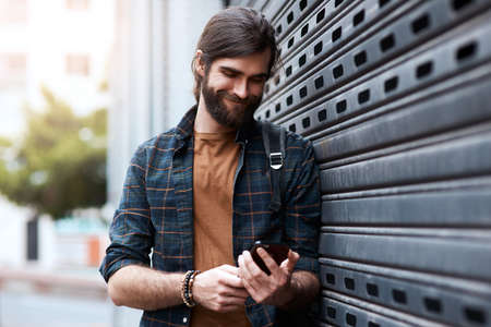 Connecting you through every walk of life. Shot of a handsome young man using his cellphone while...
