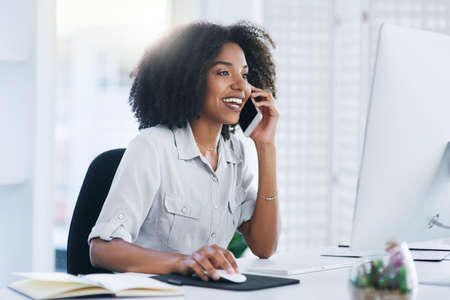 I will email you a copy of the document for your records. Shot of a young businesswoman talking on a cellphone in an office.の写真素材