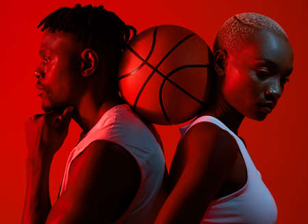 Its the support that gets us through it. Red filtered shot of a sporty young man and woman posing with a basketball in between them.の写真素材