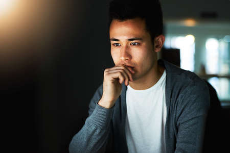 Working through the night. Shot of a handsome young male programmer working late in his office.の写真素材