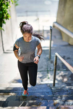 Shes stepping up her fitness routine. Shot of a fit young woman running up a flight of stairs.の写真素材