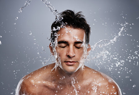 Getting clean. A young man splashing water on his face.の写真素材