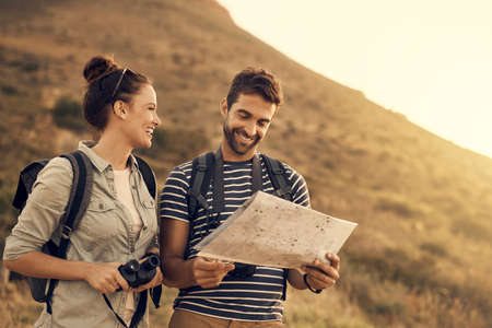 Do you even understand maps, babe. Shot of a couple looking at a map while out hiking.の写真素材