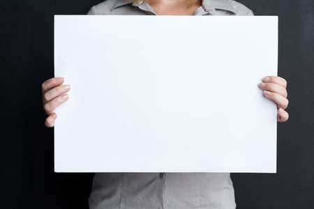 Take note. Shot of a woman holding a blank board against a dark background.の写真素材