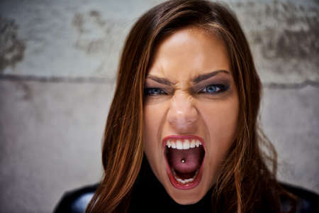 Showing her primal side. Beautiful young woman screaming violently while looking at you.の写真素材