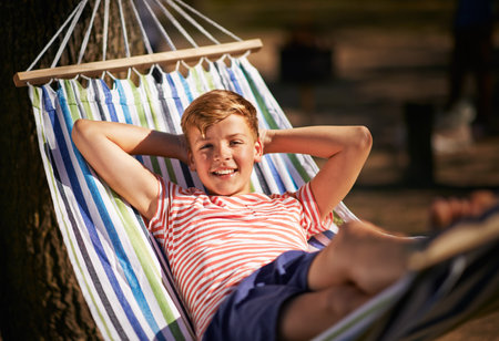 This is the life.... Shot of a young boy relaxing in a hammock.の写真素材