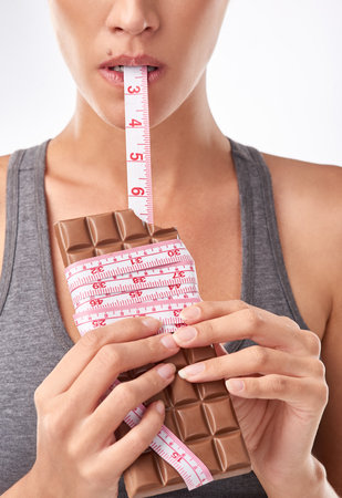 Shes a lover of chocolate. Studio shot of an attractive young woman being tempted by something sweet.の写真素材