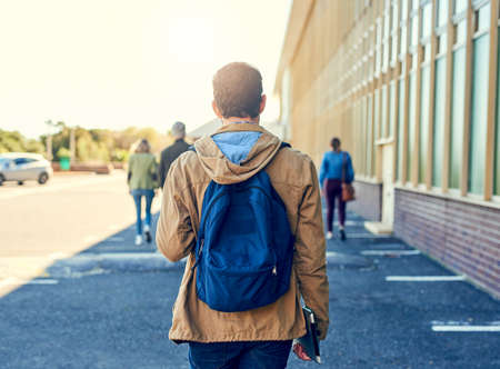 On my way to class. Shot of a college student between classes on campus grounds.の写真素材
