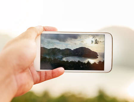 Pictures of paradise. Cropped shot of an unidentifiable person taking a picture with a smartphone while on holiday.の写真素材