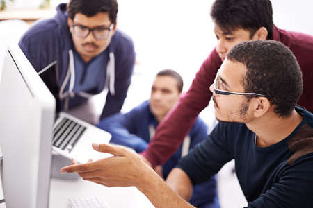 Collaborative coding. Shot of a group of colleagues working together with a computer in an office.