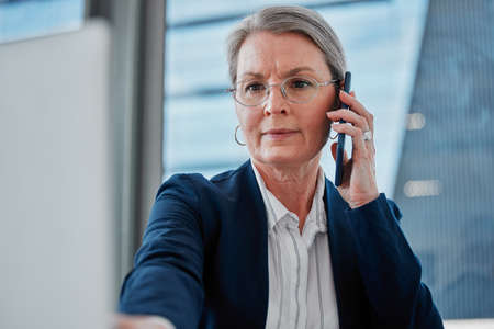 I think youve got the figures mixed up. Shot of a mature businesswoman sitting alone in the office and using technology.の写真素材