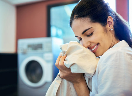 The refreshing smell of clean laundry. Cropped shot of an attractive young woman doing laundry at home.の写真素材
