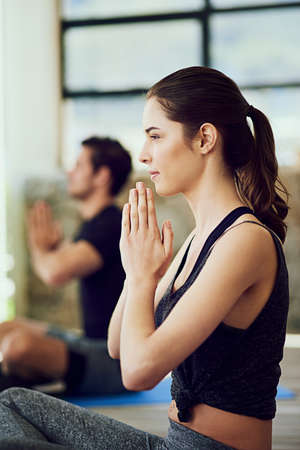 Exercising their minds and bodies. Cropped shot of two young people practising yoga indoors.
