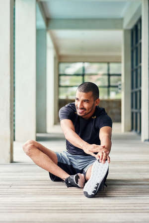 Committed to staying healthy and in shape. Shot of a sporty young man stretching outside.