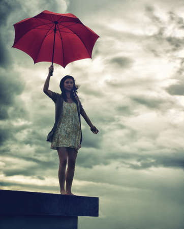 Ready to face lifes storms. Cute young woman holding an umbrella while standing on a rooftop.の写真素材