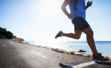 Running is a way of life. Low angle view of a runner next to the ocean.