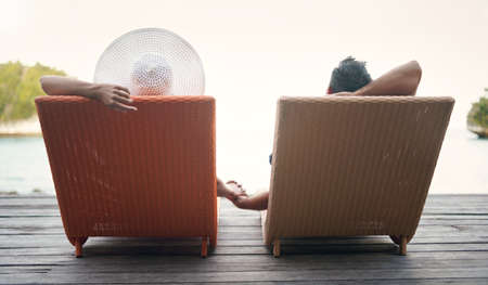 I am at peace when Im with you. Rearview shot of an unrecognizable couple sitting on sun loungers together and holding hands while on vacation.の写真素材