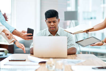 Doing his best to juggle it all. Shot of a young businessman looking stressed out in a demanding office environment.の写真素材