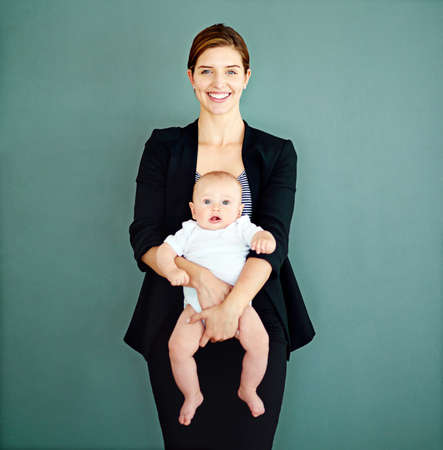 Balancing motherhood and ambition. Studio shot of a successful young businesswoman carrying her...