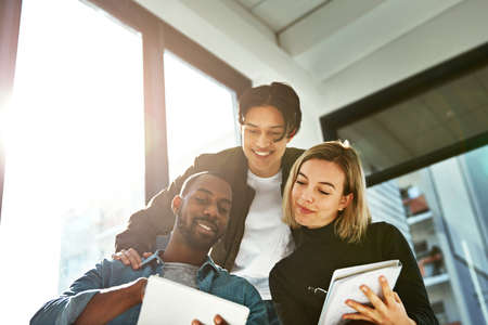 Brainstorming made simple with wireless technology. Shot of a group of young businesspeople...