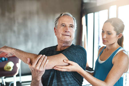 Get moving, get mobile. Shot of a senior man working out with the help of an instructor.