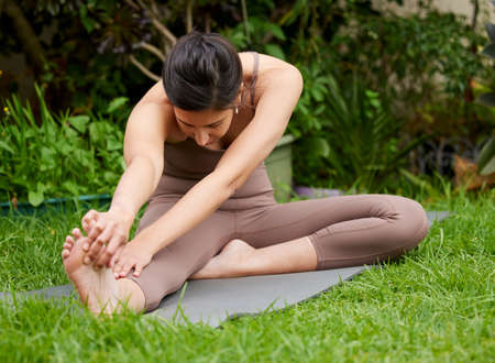 Regular movement is good for your body. Shot of a young woman stretching her legs while exercising...
