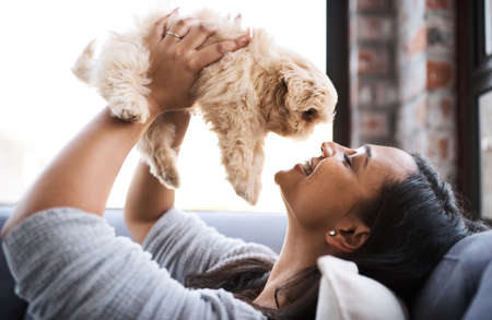 I will always woof you. Shot of a young woman relaxing with her dog at home.の写真素材