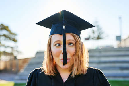Goofing around on graduation day. Portrait of a student sticking out her tongue while wearing a...