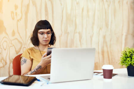 Sending a few messages to some friends at the office. Shot of a young designer using her cellphone...