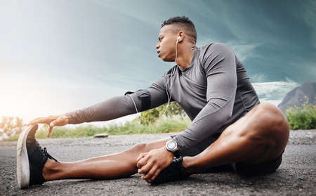 Your muscles need to wake up first. Shot of a sporty young man exercising outdoors.の写真素材