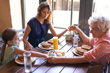 They are a devout family. Shot of the female members of a multi-generational family saying grace.
