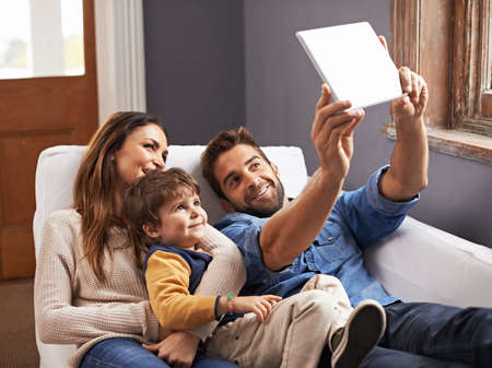 Movie time in the modern age. Shot of a happy family using a digital tablet together.の写真素材