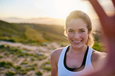 Selfie-worthy scenery. Shot of an attractive young woman taking a selfie while exercising outdoors.の写真素材